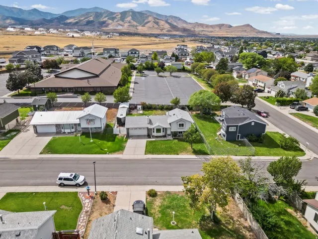 Mountain backdrop, established neighborhood, residential street, paved driveway, green lawn