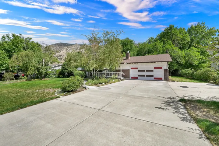Concrete driveway with an integrated two-car garage, brick accents, and mature landscaping
