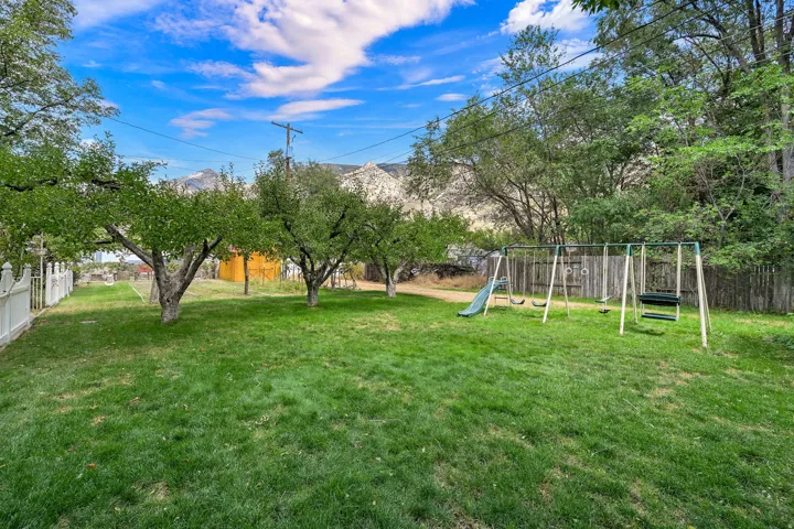 Expansive lawn with mature trees and a white picket fence