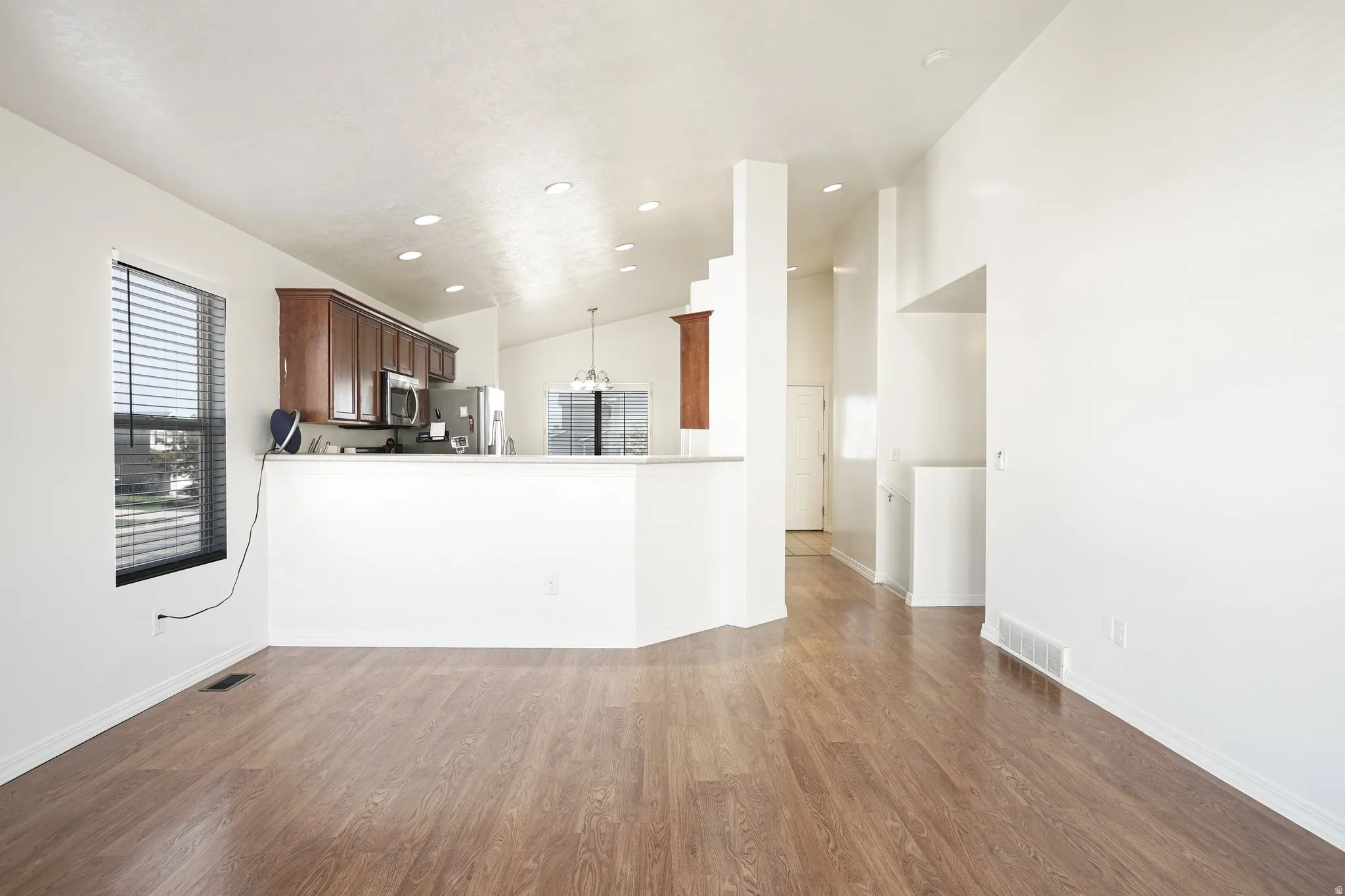 Wood-finish flooring throughout, vaulted ceiling, recessed lighting, and a kitchen featuring stainless steel appliances and wood cabinetry
