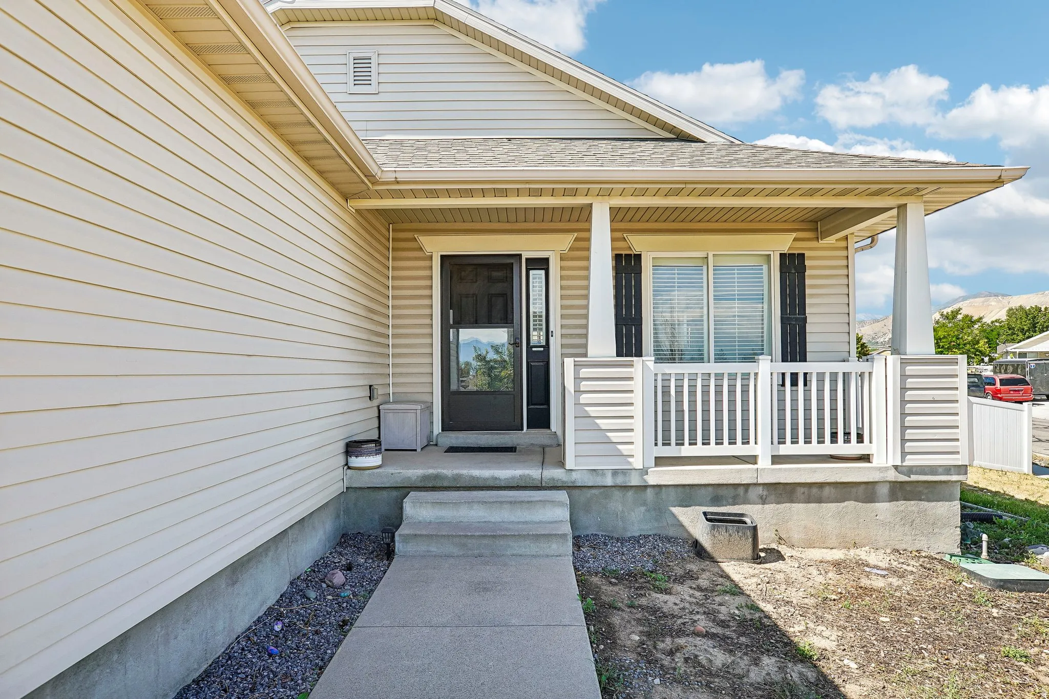 Covered front porch with white railings, a dark entry door, and light-colored siding