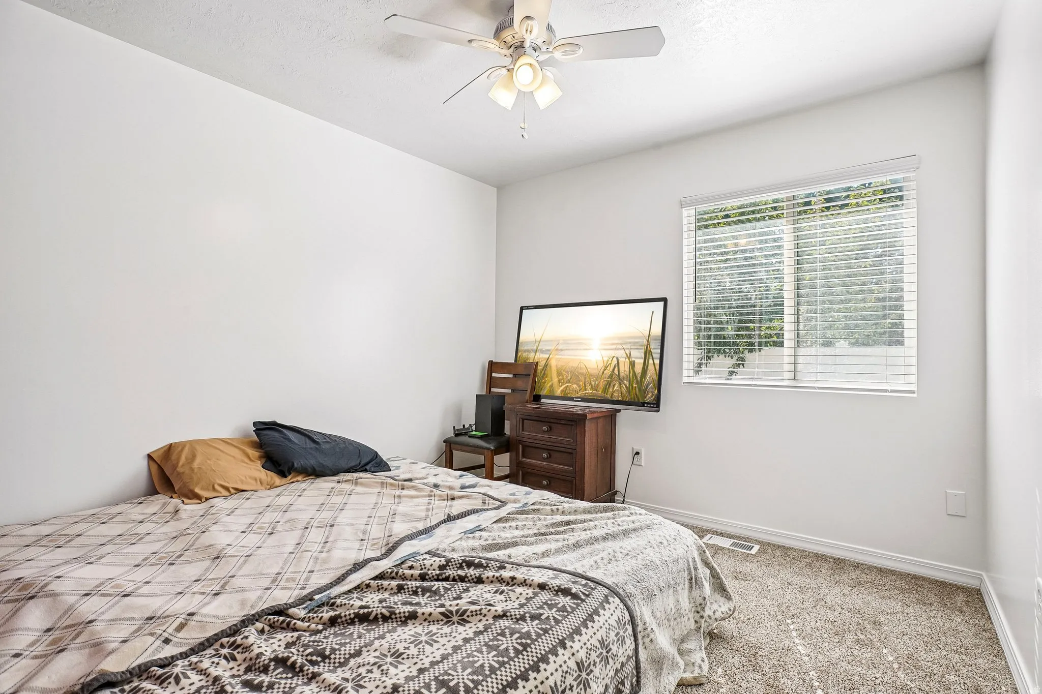 Neutral wall color, window with horizontal blinds, overhead ceiling fan, and carpeted flooring