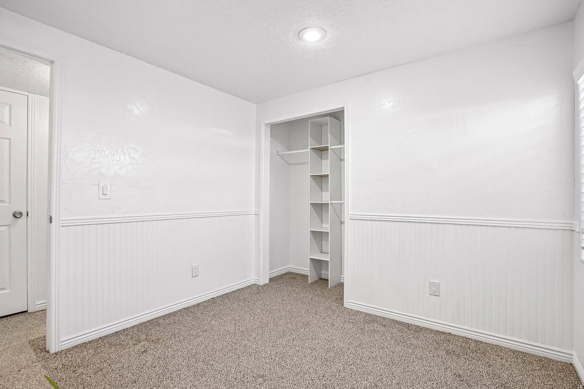 Wall-to-wall carpeting, recessed ceiling lighting, and beadboard wainscoting