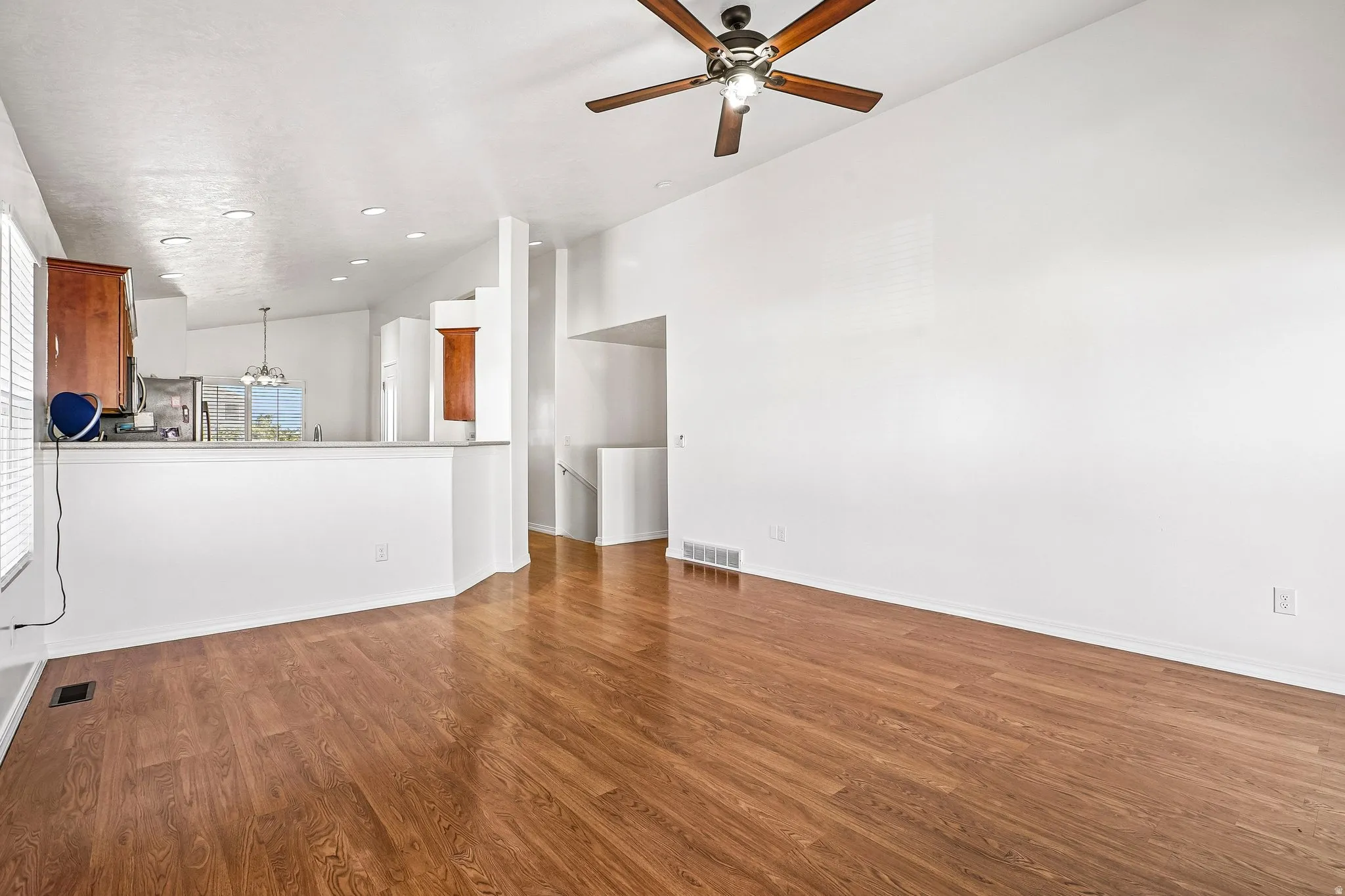 Wood-finish flooring, vaulted ceiling, and a ceiling fan with integrated lighting