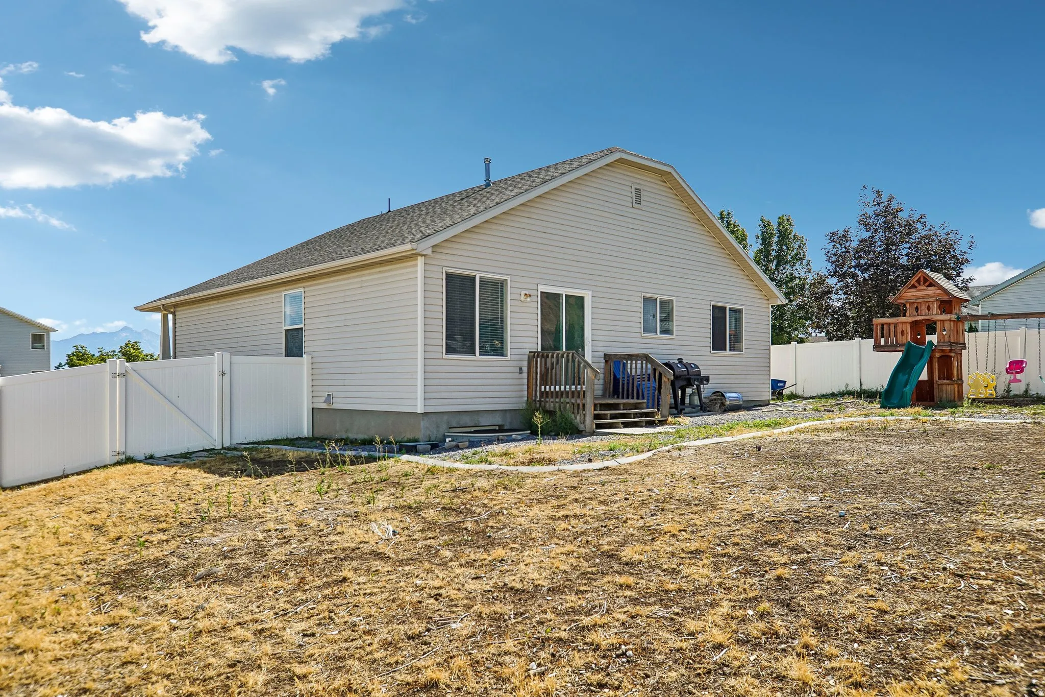 Rear exterior featuring siding, a sliding glass door, a wood deck, and a privacy fence