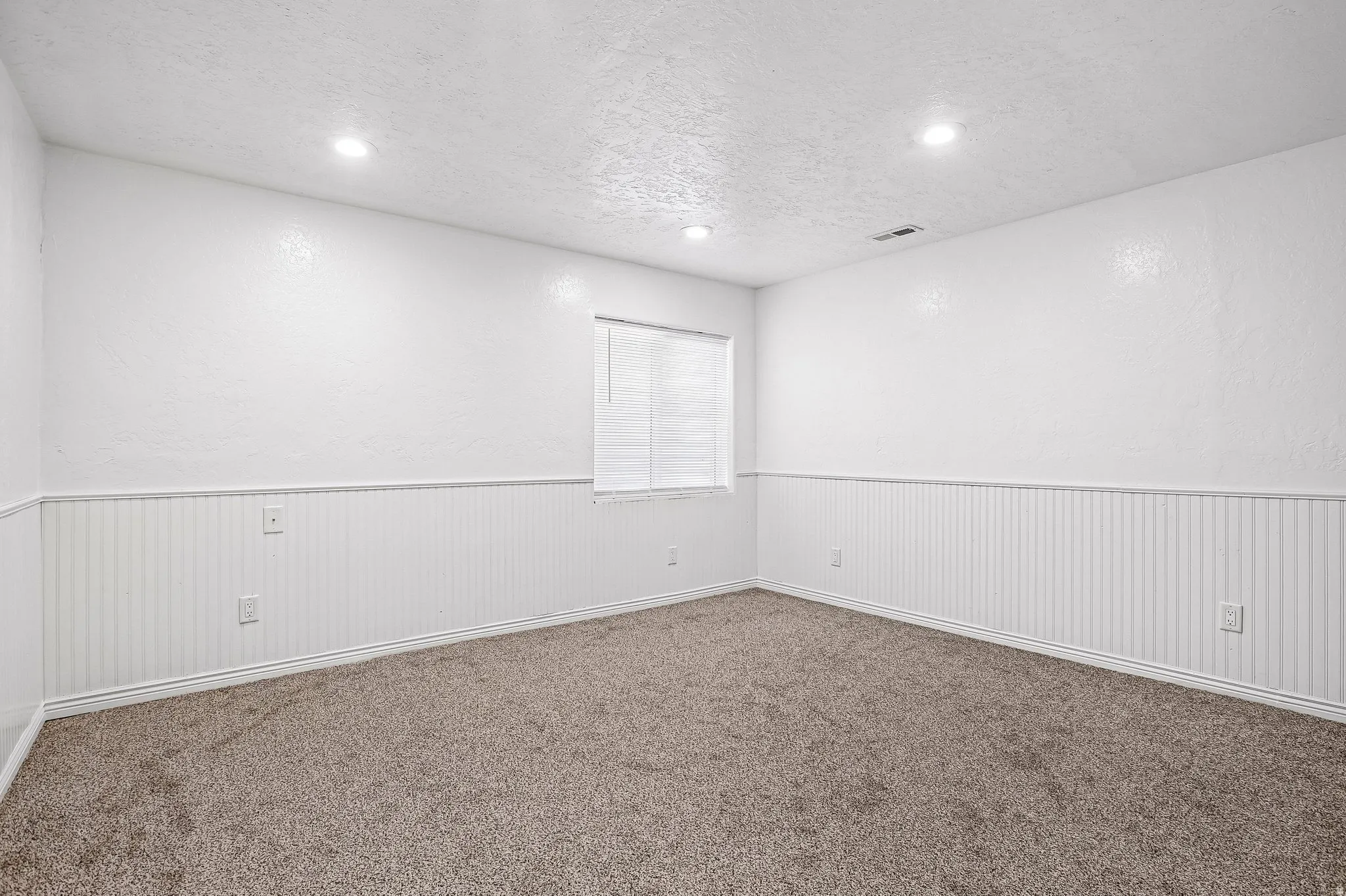 Wall-to-wall carpeting, recessed ceiling lighting, and beadboard wainscoting