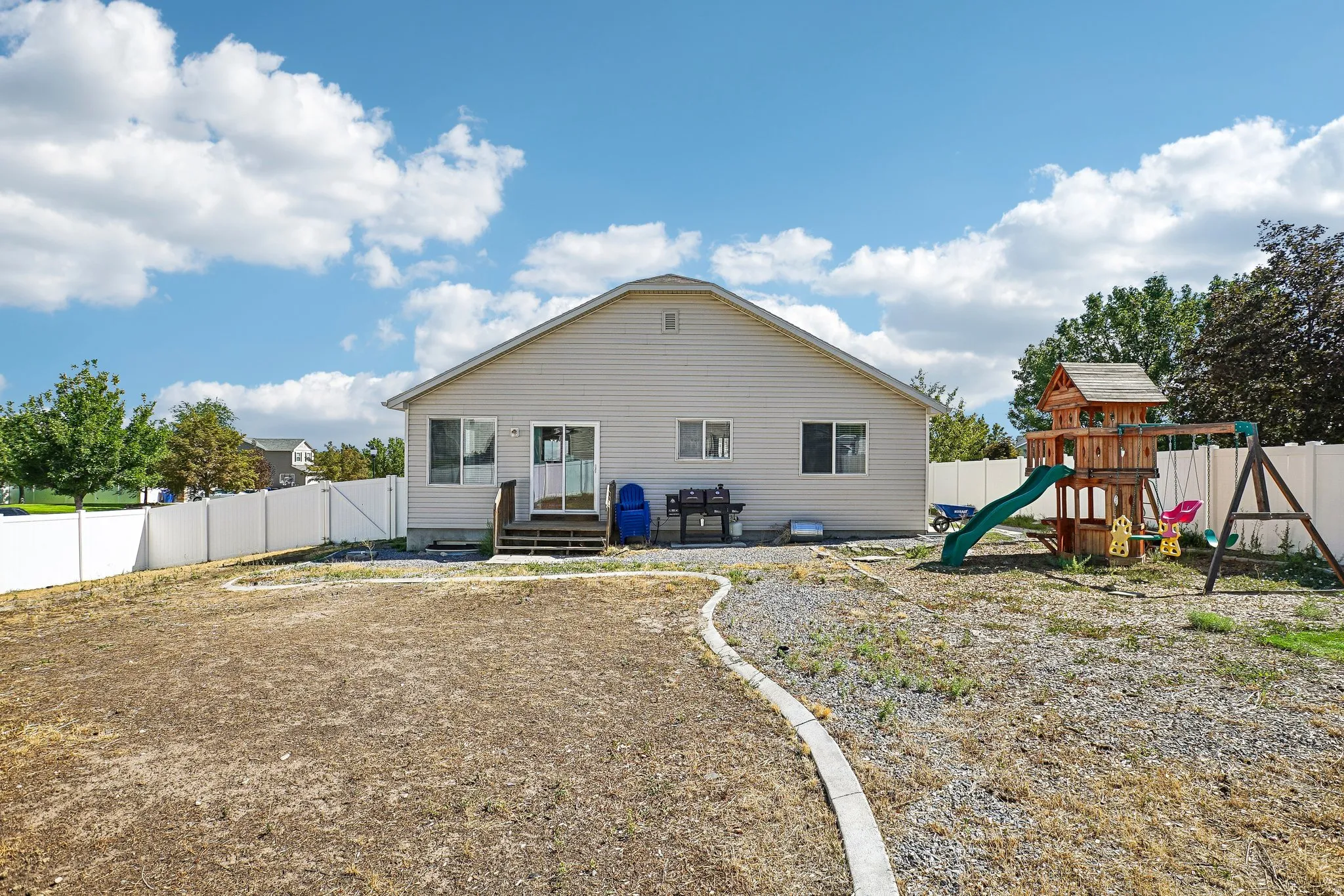 Rear exterior featuring siding, white privacy fencing, and a ground-level deck with sliding glass door access