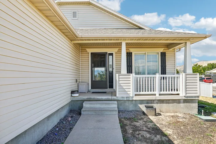 Covered front porch with white railings, a dark entry door, and light-colored siding