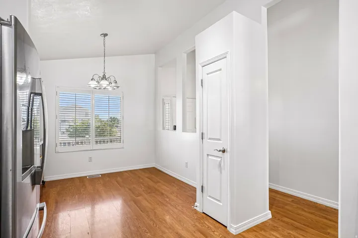 Dining space featuring wood-finish flooring, a contemporary chandelier, and a window with plantation shutters