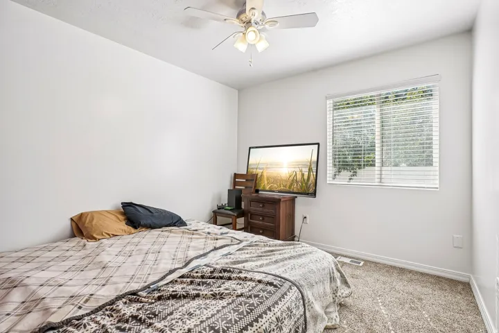 Neutral wall color, window with horizontal blinds, overhead ceiling fan, and carpeted flooring