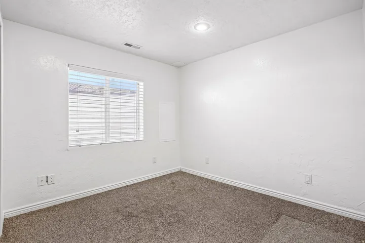 Recessed lighting, textured walls, window with blinds, and neutral carpet