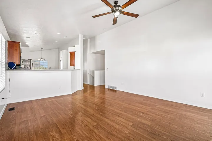 Wood-finish flooring, vaulted ceiling, and a ceiling fan with integrated lighting