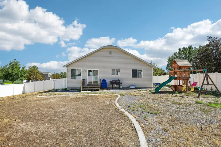 Rear exterior featuring siding, white privacy fencing, and a ground-level deck with sliding glass door access