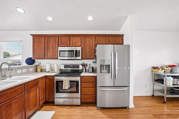 Kitchen featuring recessed lighting, wood-finish flooring, stainless steel appliances, and wood cabinetry with a light-toned countertop
