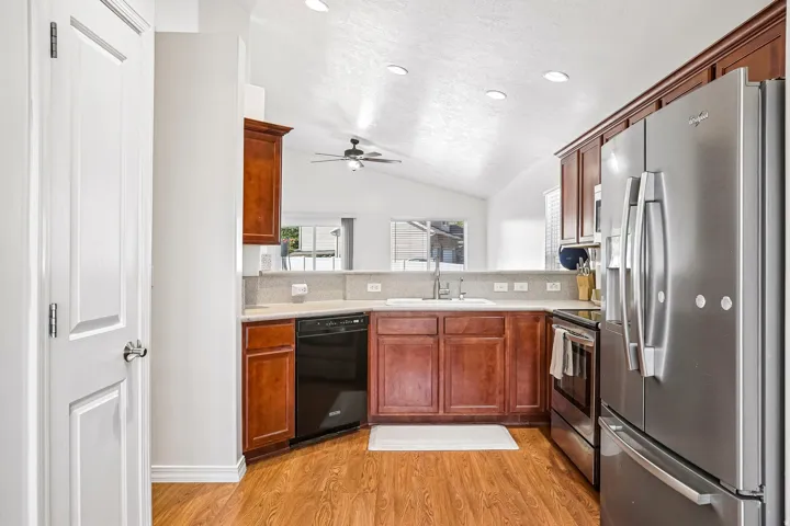 Kitchen featuring wood-finish flooring, stainless steel appliances, recessed lighting, wood cabinetry, and a vaulted ceiling