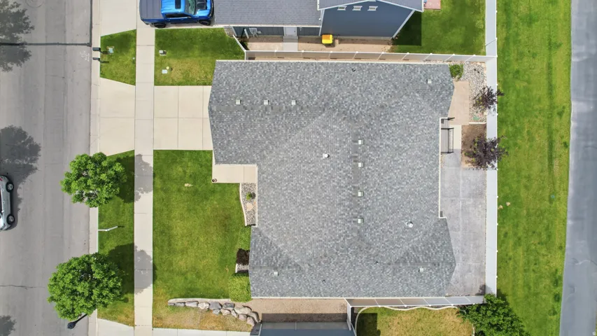 Asphalt shingle roofing, paved driveway, concrete sidewalks, and landscaped grounds