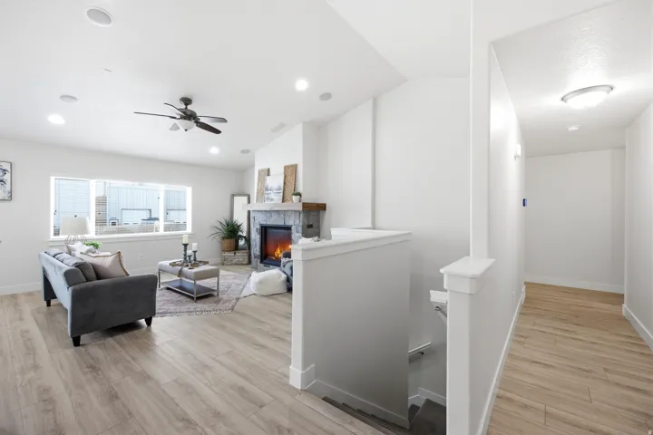 Open concept living area with wood-finish flooring, a stone-clad fireplace, and a wood mantel