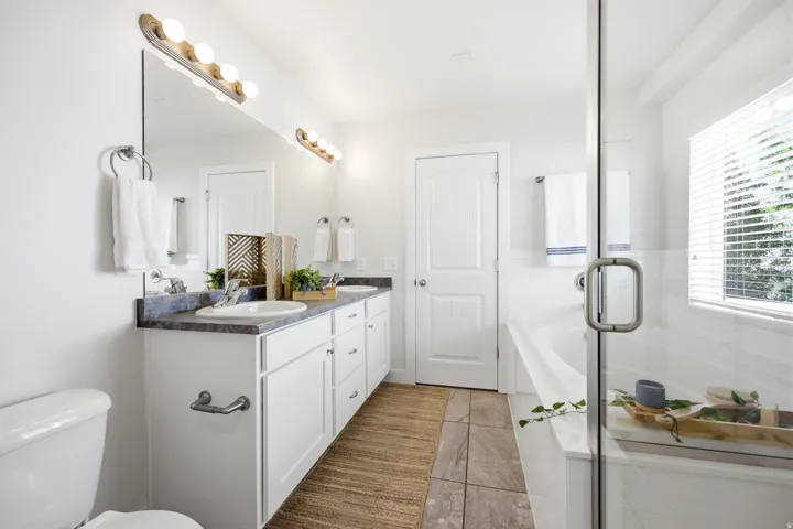 Dual vanity with undermount sinks, an integrated bathtub, a glass-enclosed shower, and a privacy window