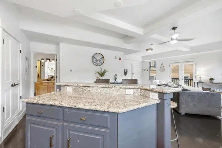 Kitchen island with granite countertops, recessed-panel cabinetry, and gold-tone hardware