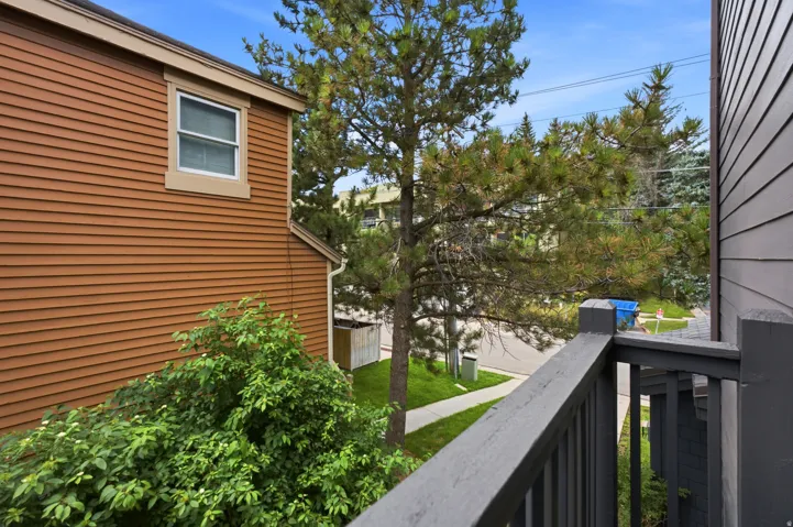 Balcony with dark painted wood railing overlooking a residential street