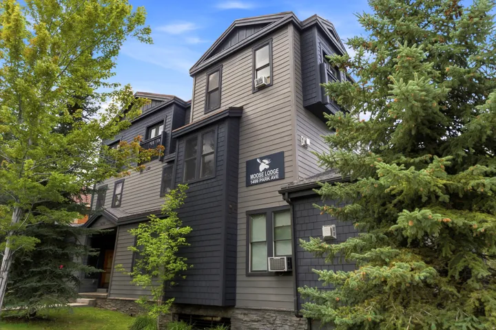 Multi-story exterior with varied siding textures, multiple window units, and mature landscaping