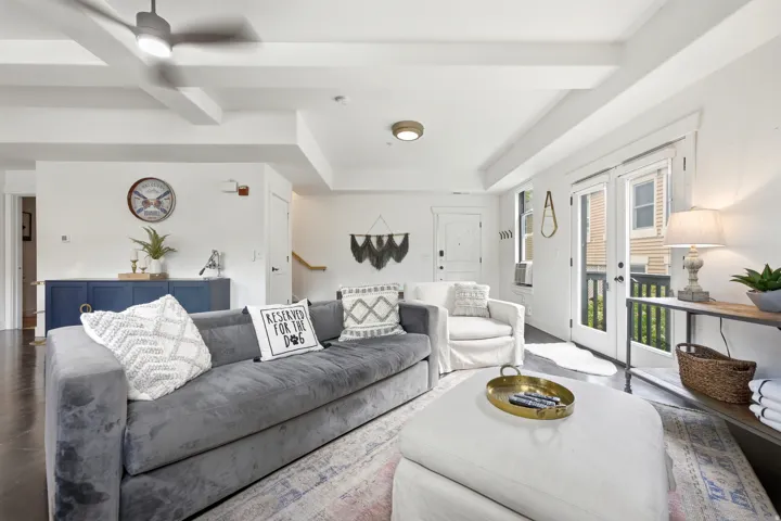Spacious living area featuring exposed ceiling beams and dark wood-finish flooring
