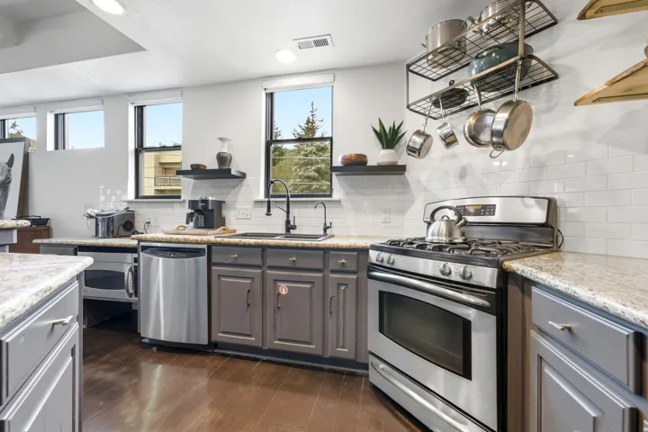 Kitchen featuring stainless steel appliances, wood-finish flooring, white subway tile backsplash, and light-toned countertops