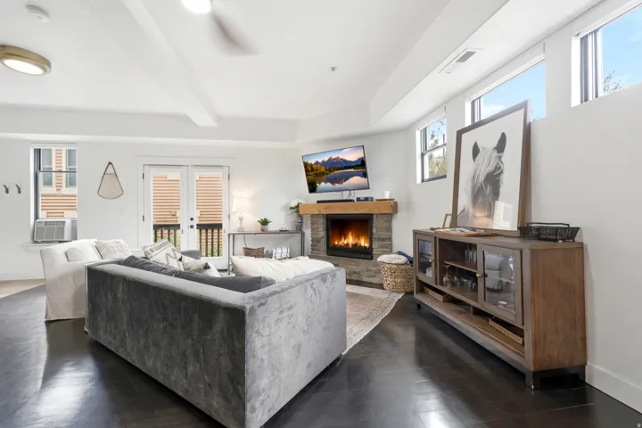 Dark wood-finish flooring with a stacked stone fireplace and wood mantel