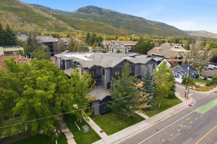 Multi-level property with dark-toned exterior siding and multiple gabled rooflines, situated near a paved road with a dedicated lane