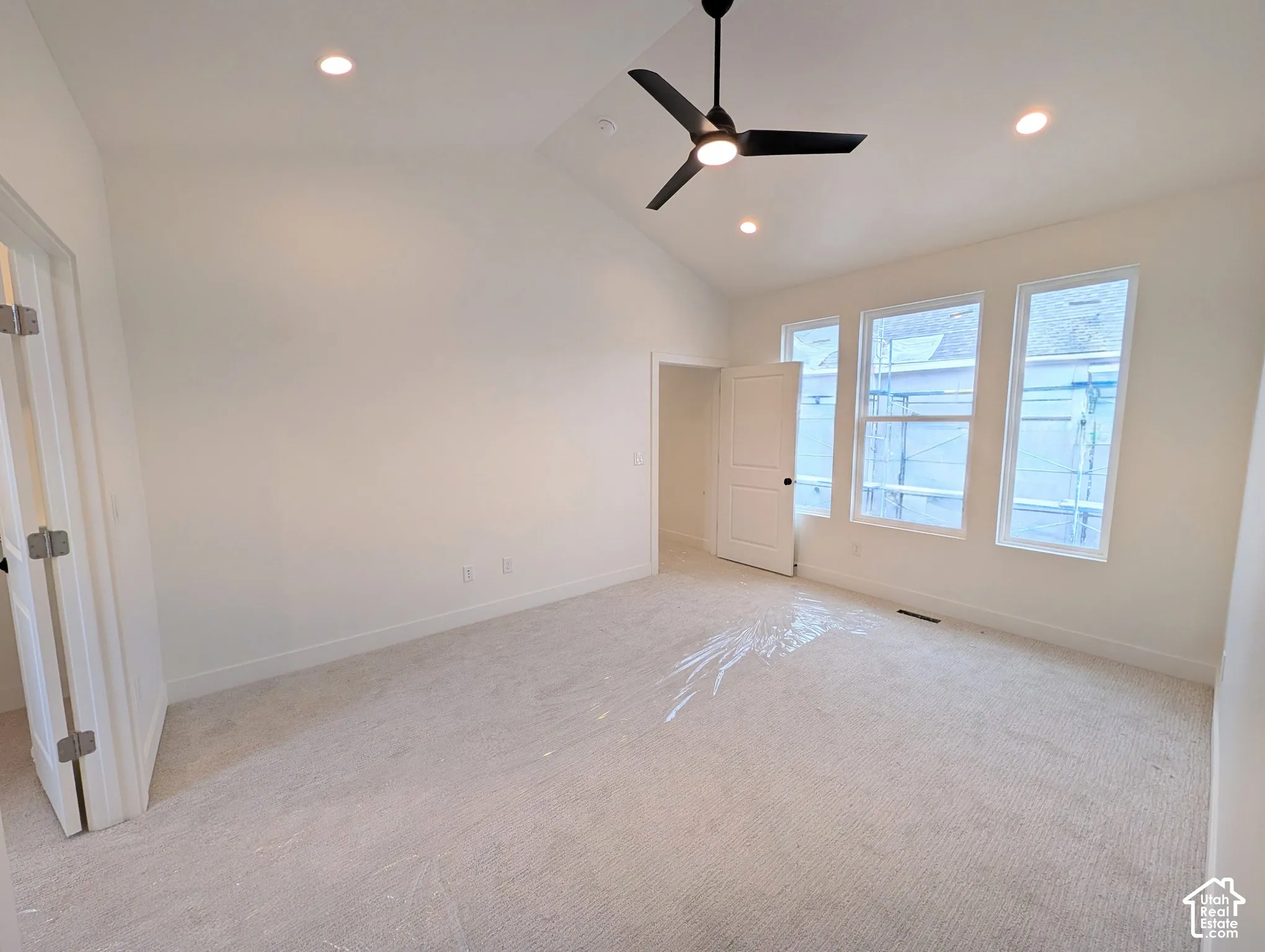 Vaulted ceiling with recessed lighting and a ceiling fan, multiple windows, and light-toned carpeting