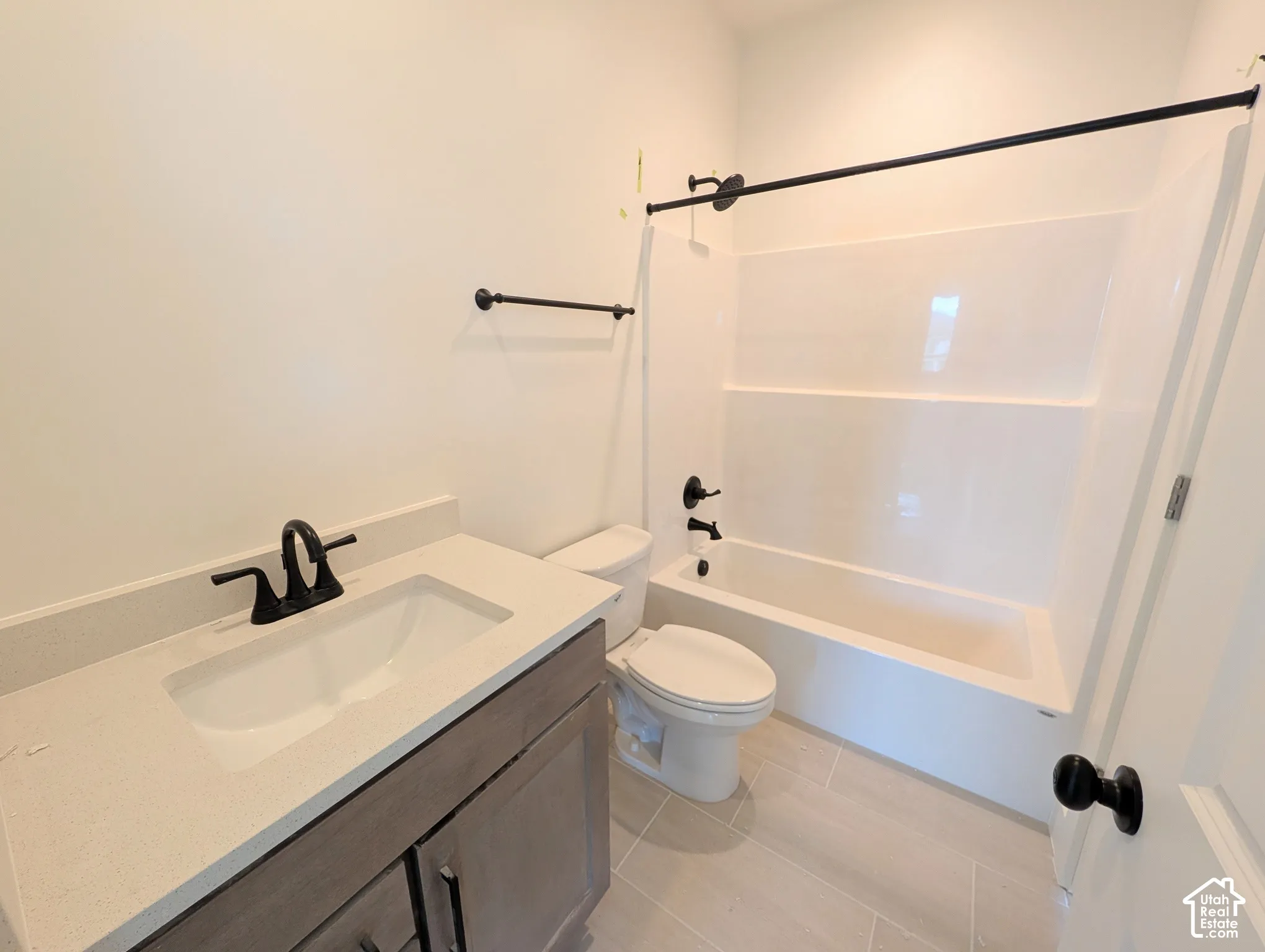 Bathroom featuring a single vanity with light-toned countertop, integrated sink, and dark-finish faucet