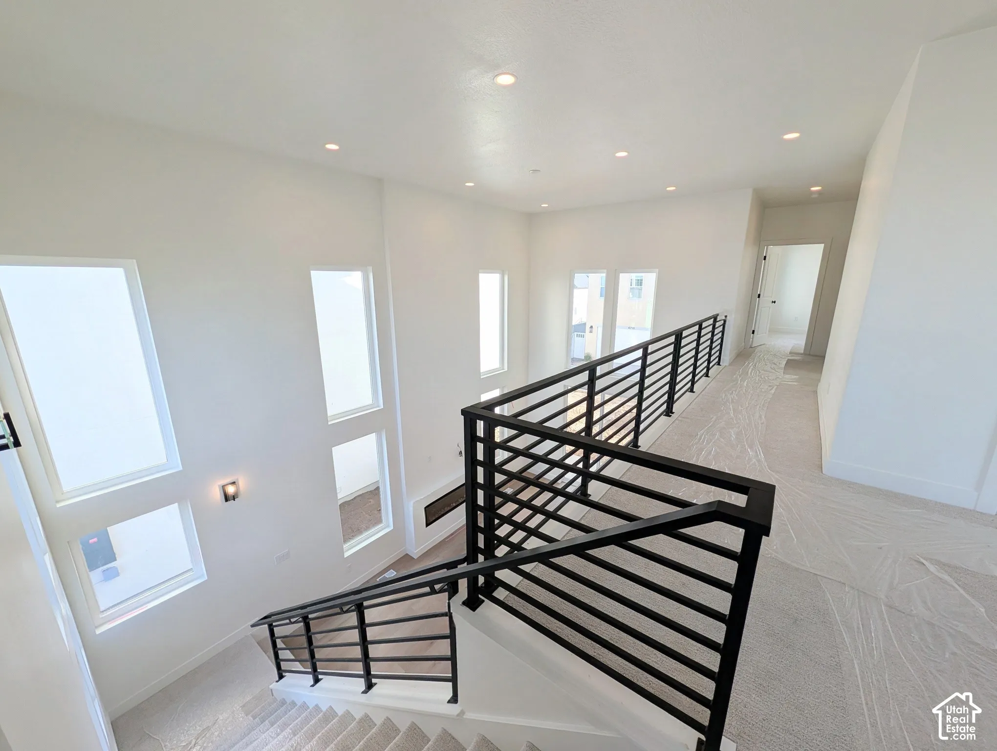 Multi-level interior featuring modern iron railings, recessed ceiling lighting, and multiple vertical windows