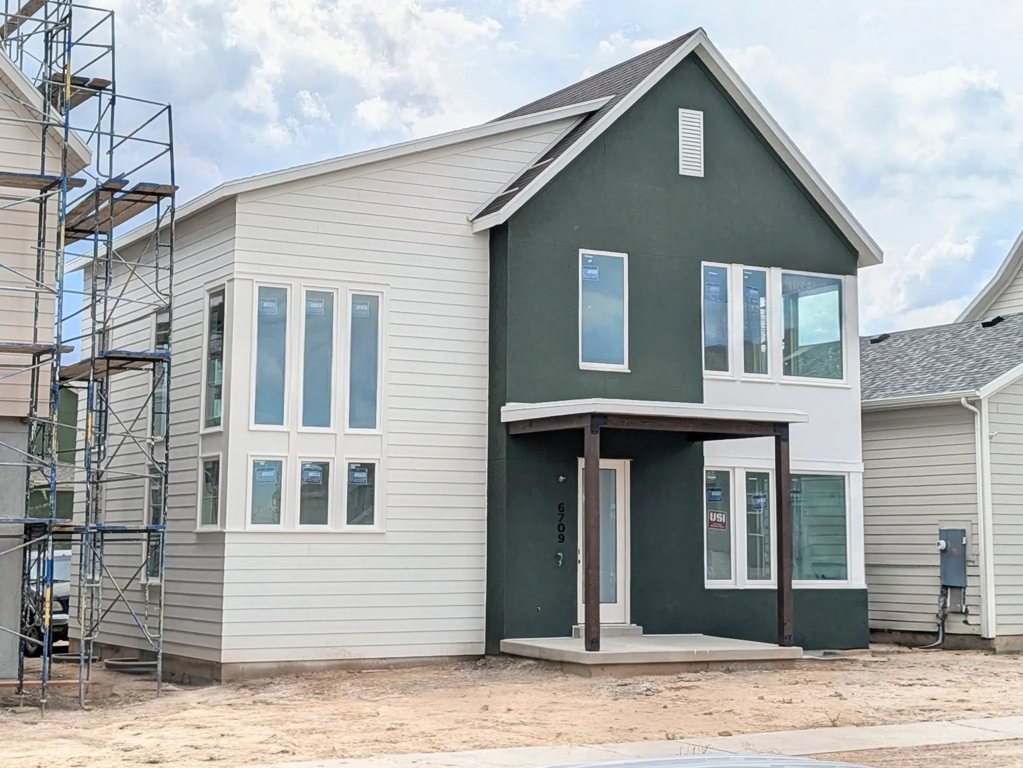 Two-story exterior with white horizontal siding and a dark green stucco accent