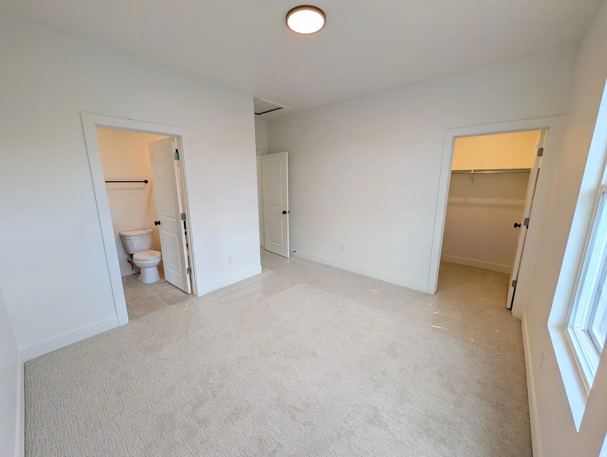 Bedroom #3. Neutral-toned carpeting, white walls, flush-mount ceiling light, window, and a closet with shelving