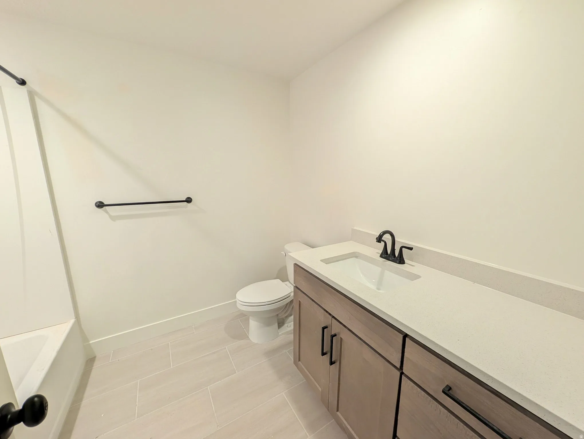 Bathroom featuring a single-sink vanity with wood-finish cabinetry, a white countertop, and a black faucet