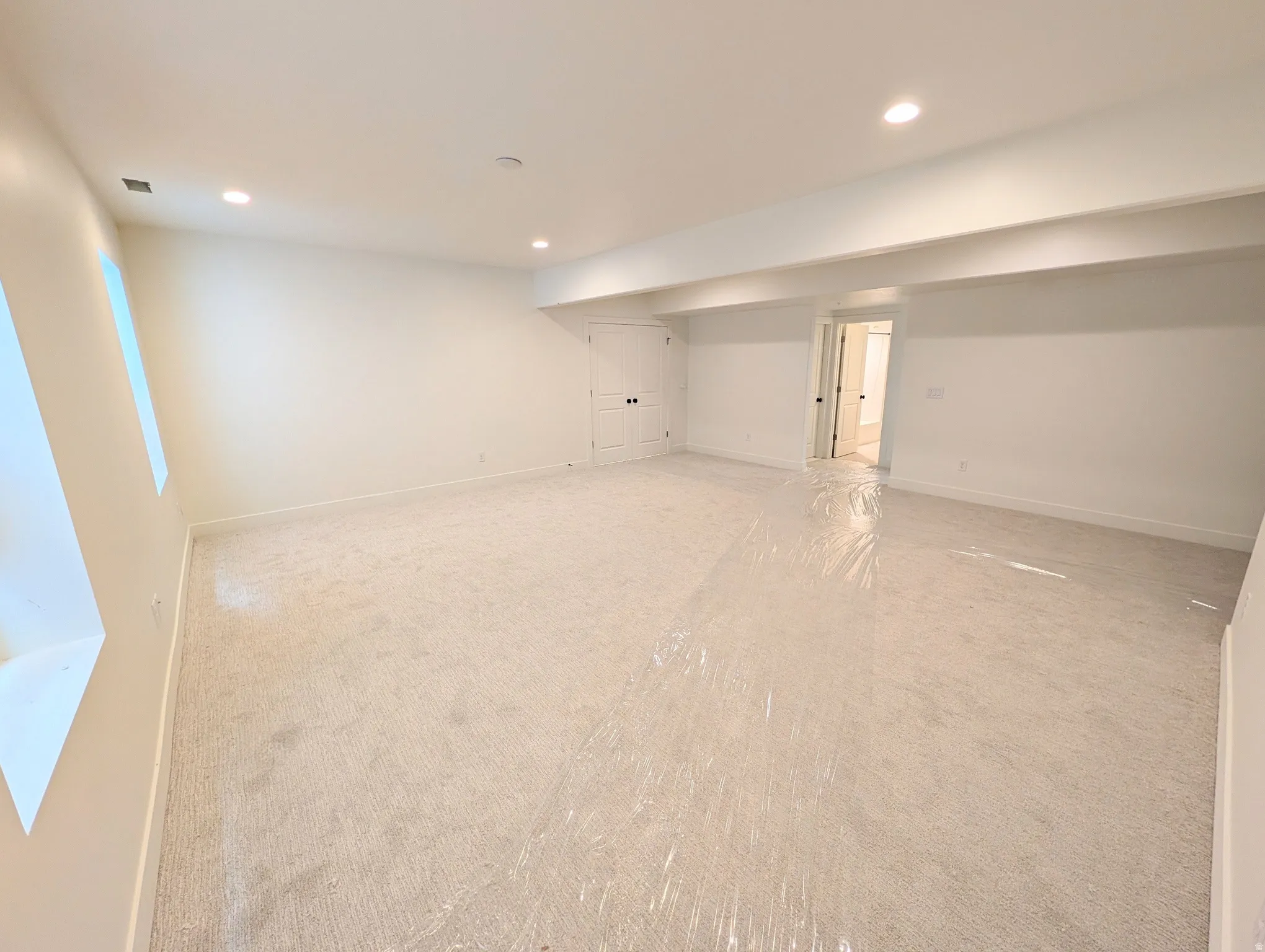 Recessed lighting, light-toned carpeting, and white walls