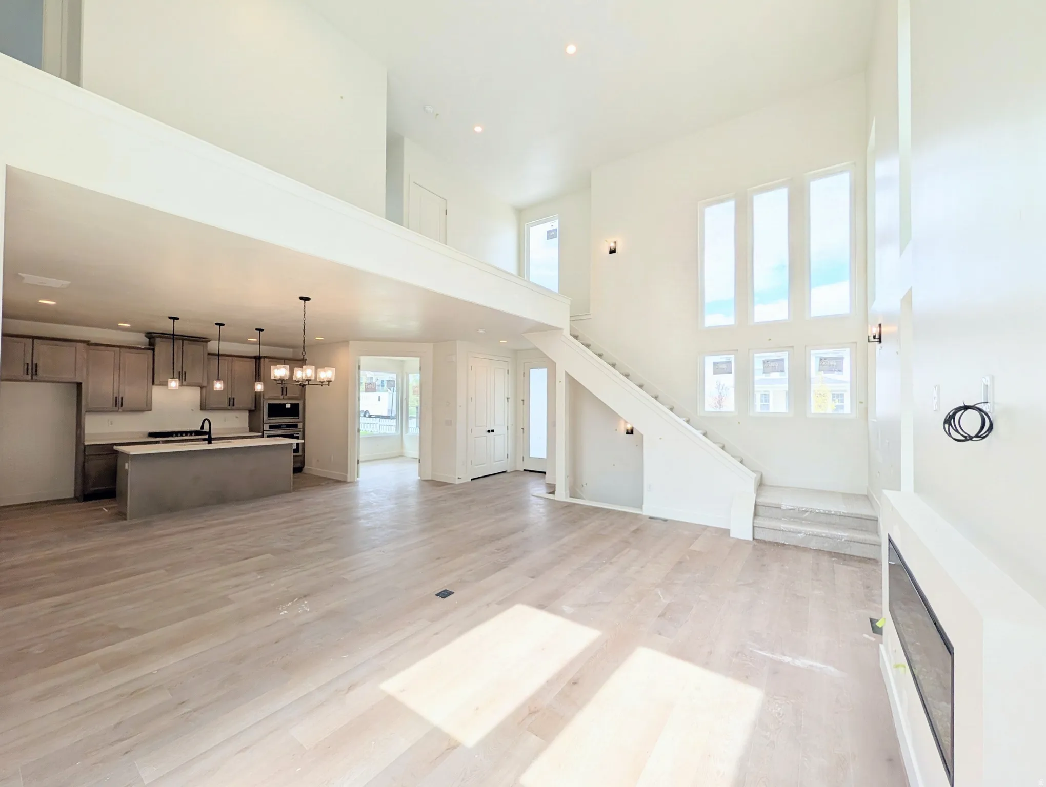 Open-concept living area featuring high ceilings, light wood-finish flooring, and a modern fireplace