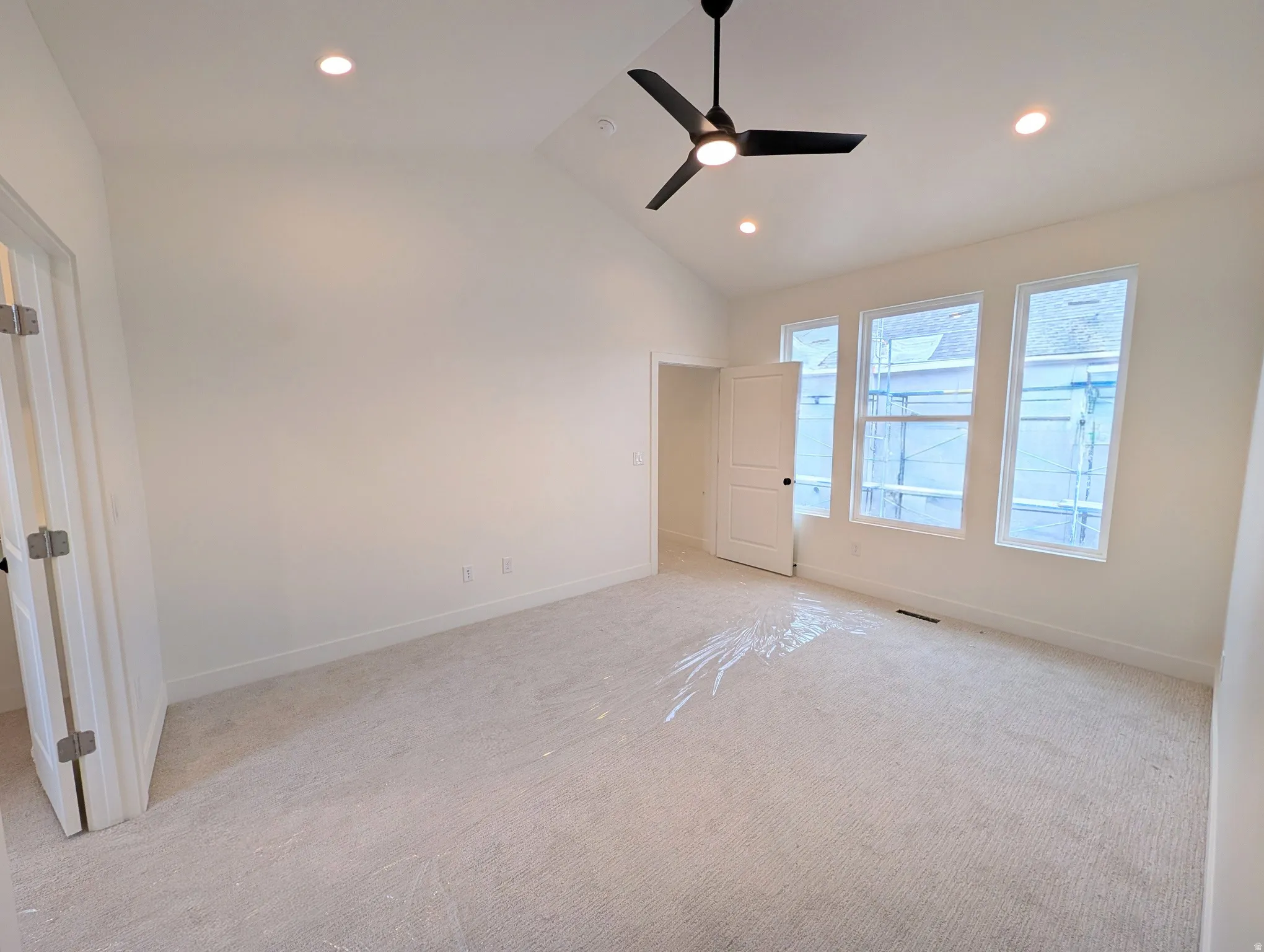 Vaulted ceiling with recessed lighting and a ceiling fan, multiple windows, and light-toned carpeting