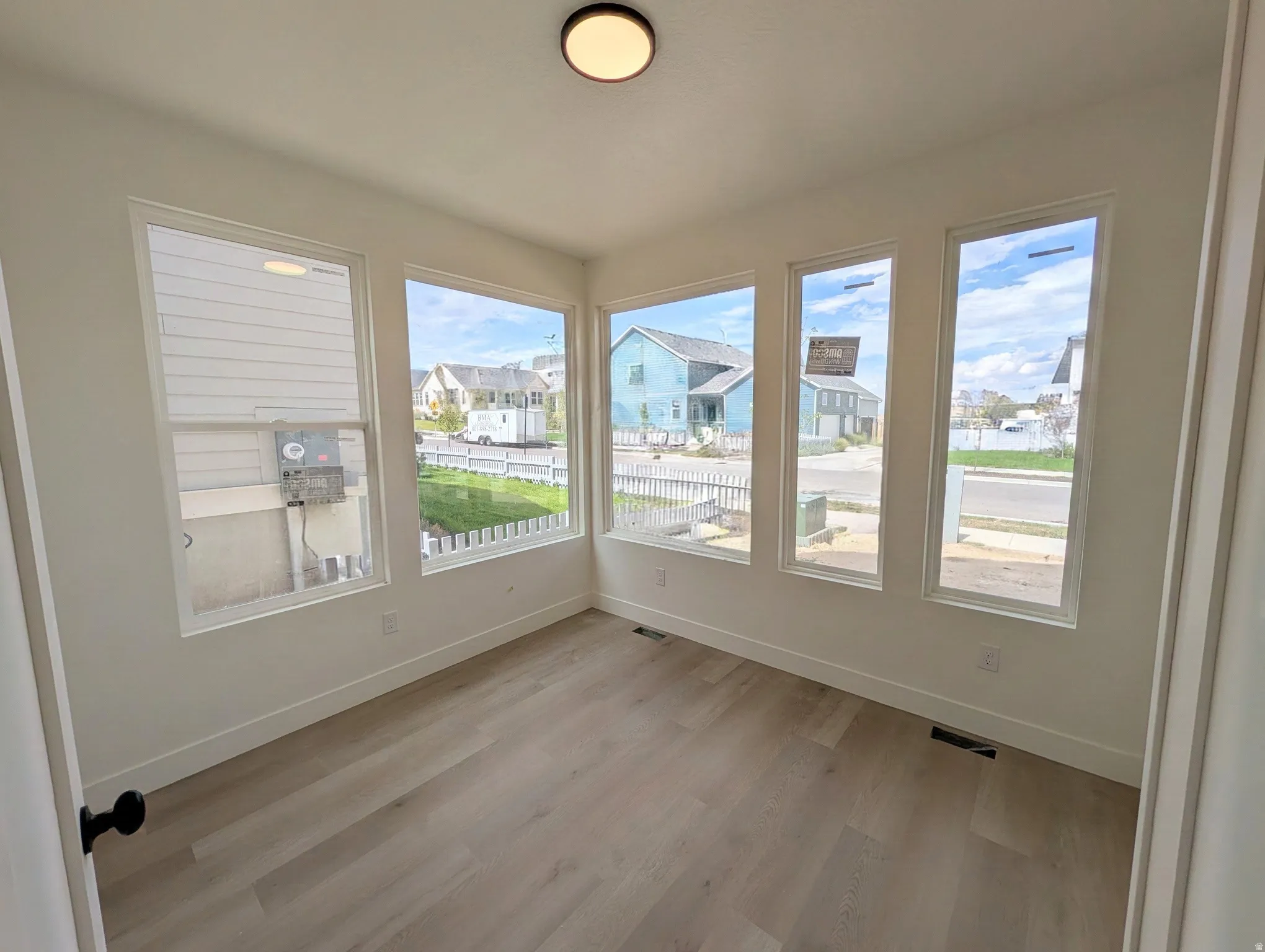 Sunlit bonus room featuring multiple casement windows with expansive natural light, wood-finish flooring throughout, and clean architectural lines with neutral wall finishes