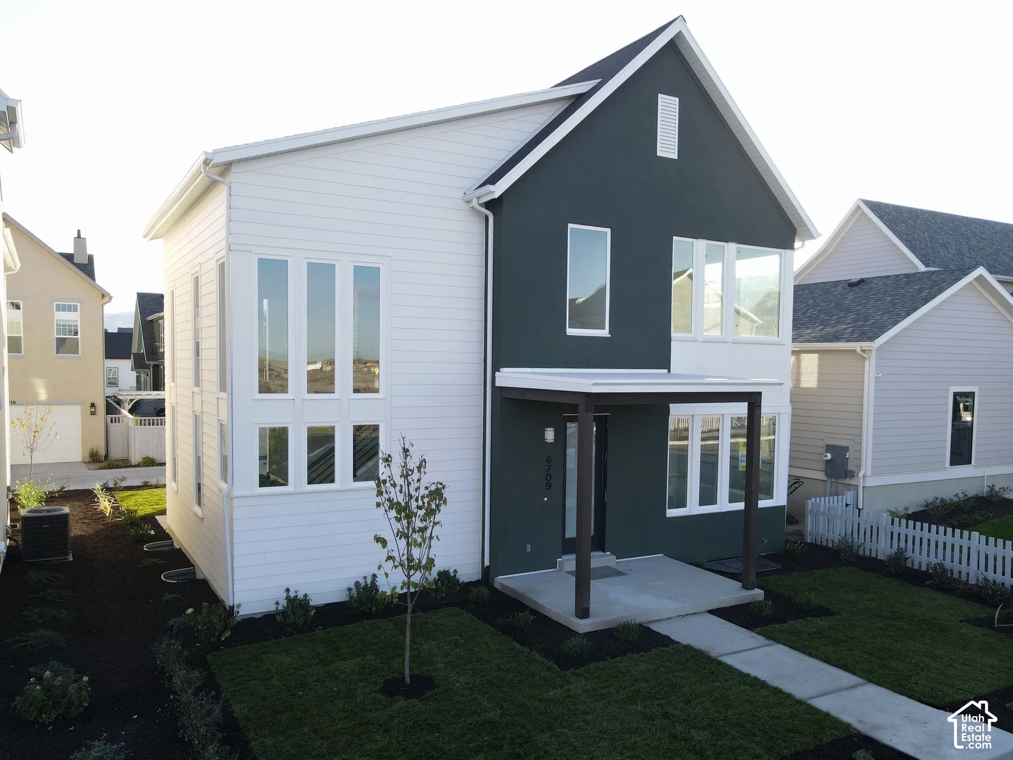 Modern facade with contrasting dark and light siding, an inviting covered entry, and expansive windows