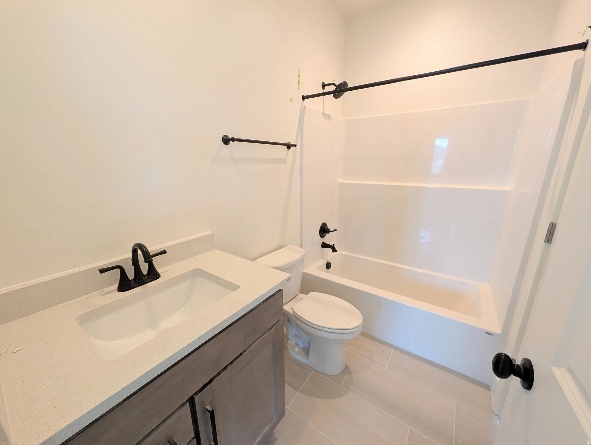 Bathroom featuring a single vanity with light-toned countertop, integrated sink, and dark-finish faucet