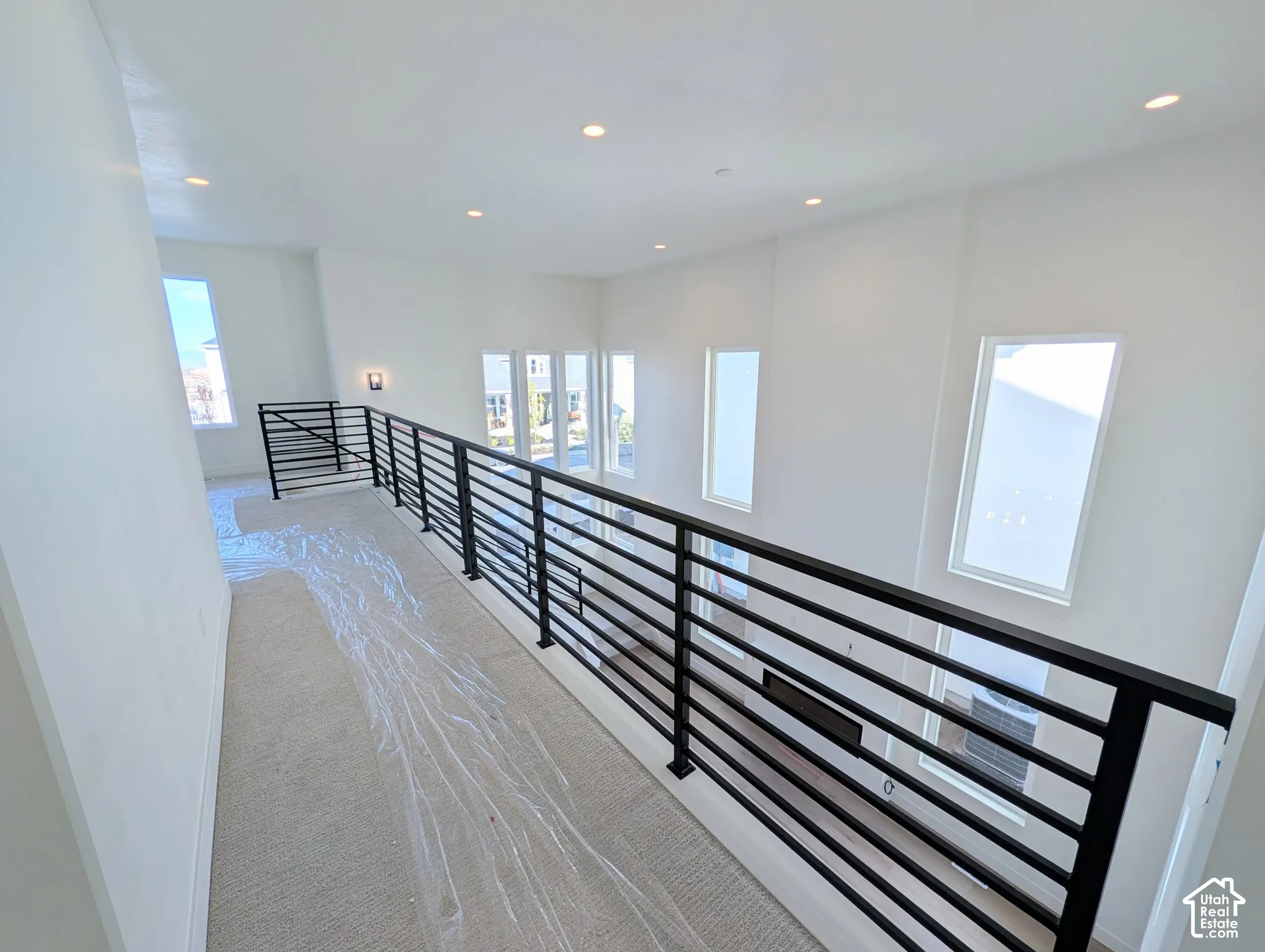 Contemporary horizontal-bar railing system, recessed lighting, wall sconce, and multiple windows