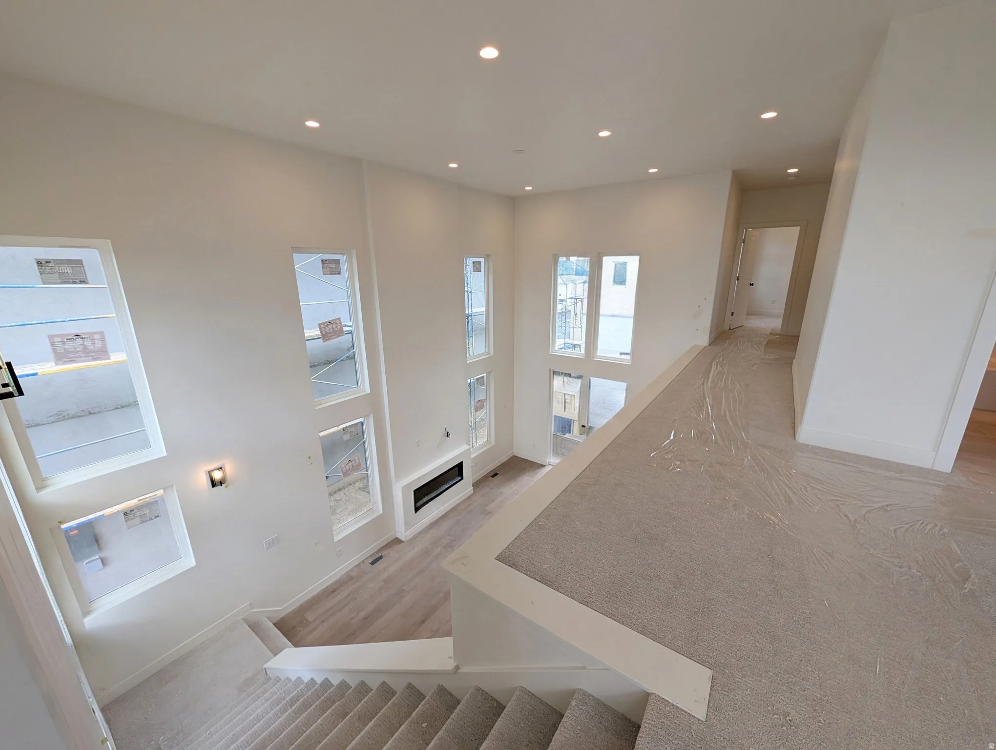 Two-story living area with multiple windows, recessed lighting, and a linear fireplace