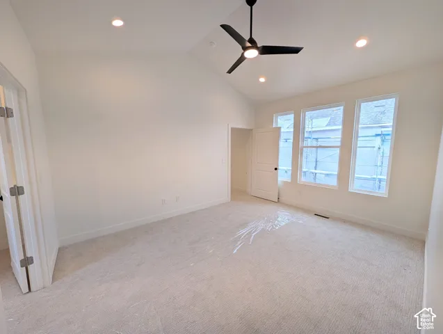 Vaulted ceiling with recessed lighting and a ceiling fan, multiple windows, and light-toned carpeting