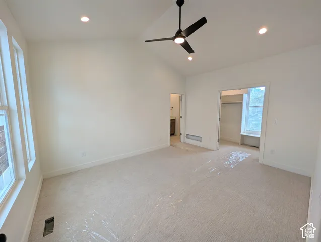 Vaulted ceiling with recessed lighting, ceiling fan, carpeted flooring, and multiple windows