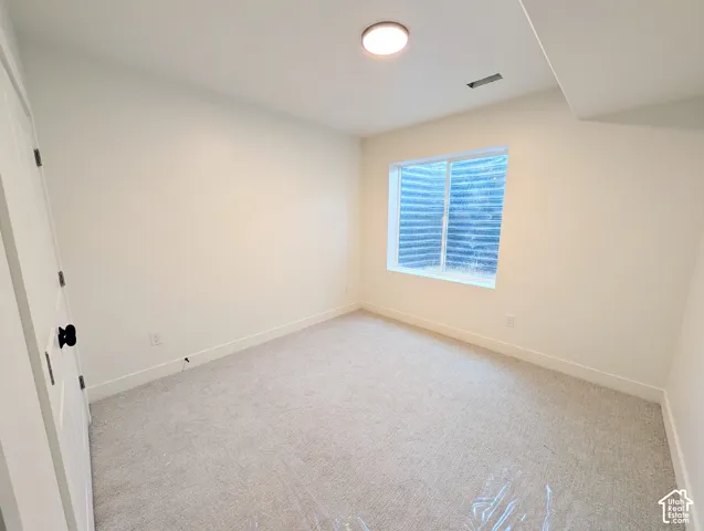 Bedroom #4-basement. Carpeted room with a window, recessed ceiling light, and white paneled door with a black knob