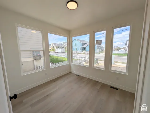 Sunlit bonus room featuring multiple casement windows with expansive natural light, wood-finish flooring throughout, and clean architectural lines with neutral wall finishes