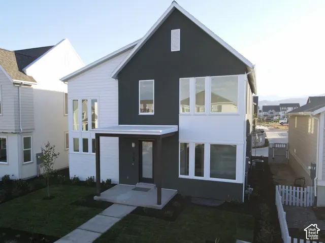 Contemporary exterior featuring a covered entry, vertical siding, multi-pane windows, and a manicured lawn