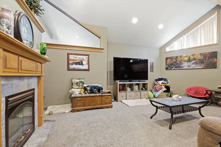 Carpeted living area featuring a fireplace with a wood mantel, tile surround, and glass screen