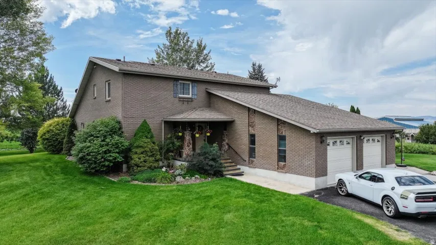 Brick exterior with a covered entry, attached two-car garage, and established landscaping